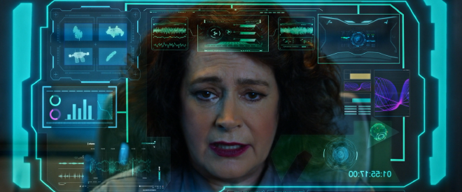 A close-up of the character Chase. She looks disappointed and a little sad. Superimposed over the image is a futuristic looking projection of charts and various data.
