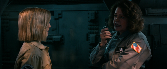 An image of the female characters Astrid and Chase, wearing their Space Force uniforms and talking in a hallway of a space station. On Chase&rsquo;s arm the American Flag is clearly displayed, stitched into her uniform.