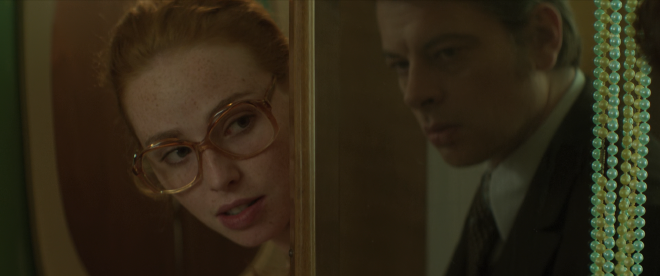 Dany is peering around the edge of closet while getting changed, Michel is on the other side of wall and shot, talking to her.