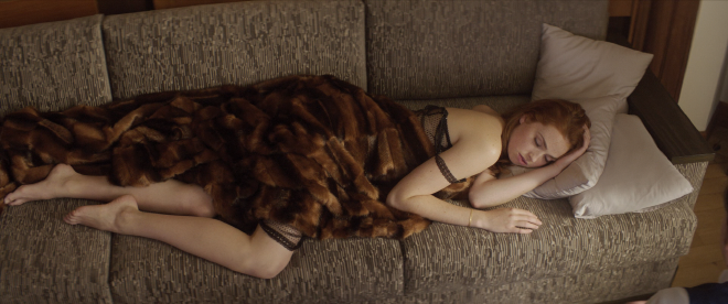Dany laying on a couch, sleeping, in the early day. A fur blanket partially covers her. Underneath she is wearing a see through piece of black lingerie.